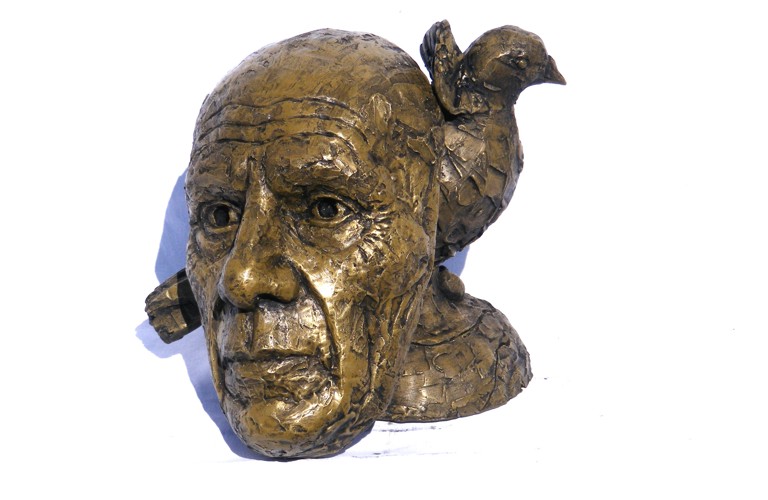 A photographs of a bust of Picasso, depicted with a bird on his head