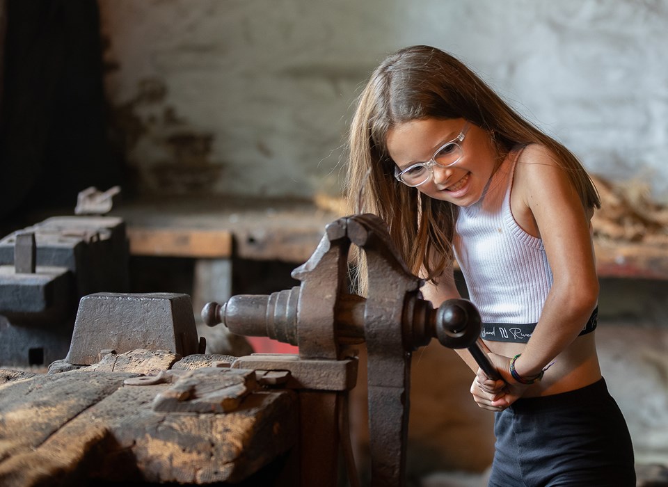 A young visitor tries a historic bench vice at Abbeydale Industrial Hamlet.