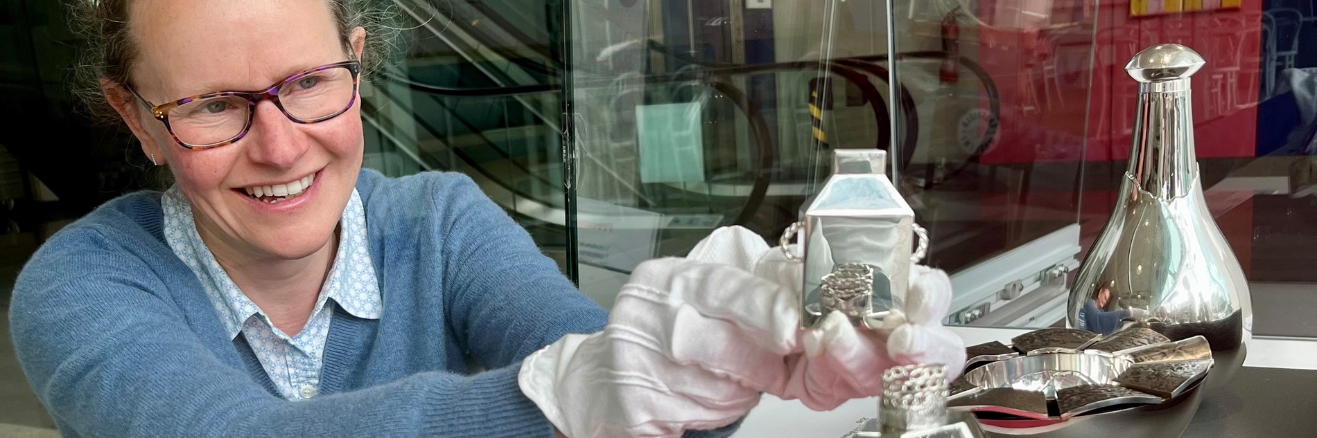 An adult installing silverware into a display case in a museum gallery 