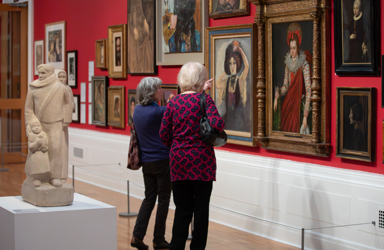 A photograph of two adults looking at artworks in a gallery. 