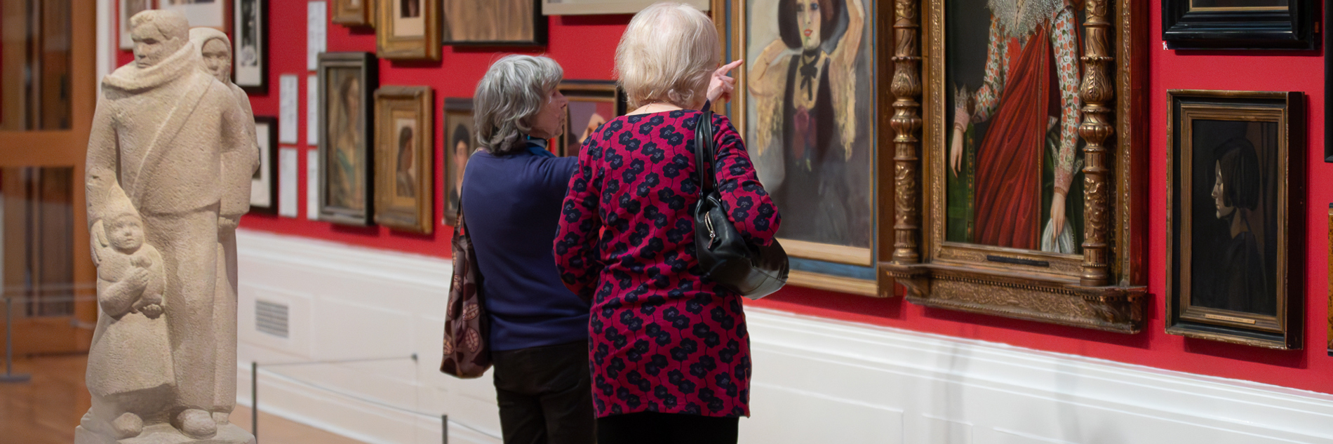 A photograph of two adults looking at artworks in a gallery. 