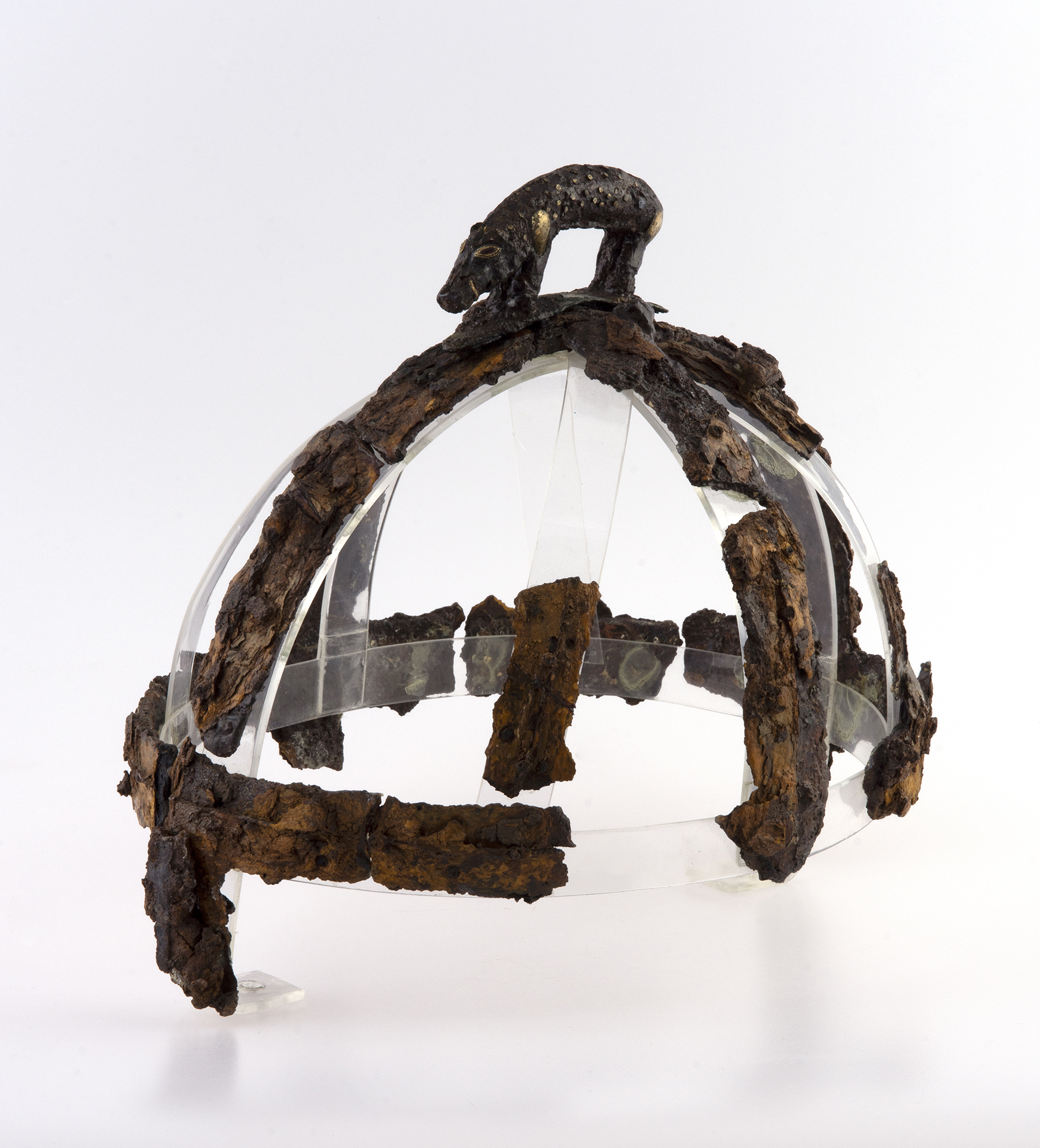 Corroded pieces of an anglo Saxon helmet reconstructed on a Perspex frame with a decorative figure of a boar on top.