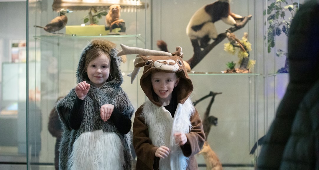 Two primary school aged children, one dressed as a deer and the other in a grey furred hooded, sleeveless outfit.