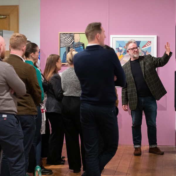 An artist talks to a group of visitors about their work work in an art gallery