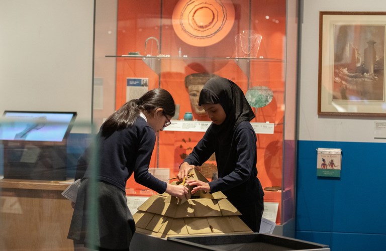 Two primary school students put together a wooden model of a pyramid, in the Ancient Egypt gallery.