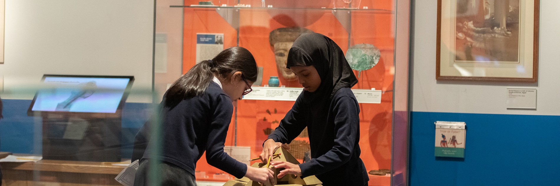 Two primary school students put together a wooden model of a pyramid, in the Ancient Egypt gallery.