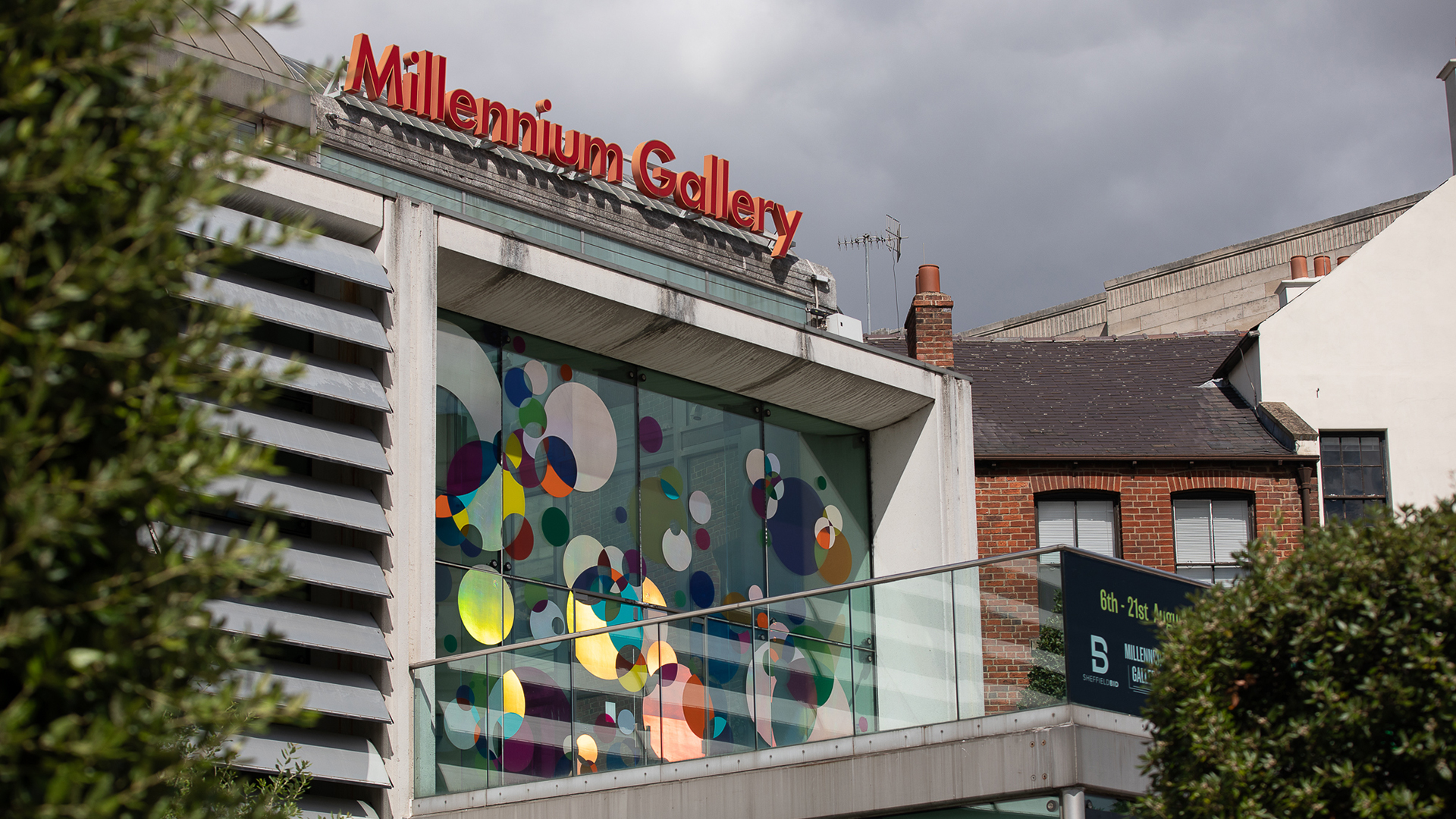 The external, upper glass door and windows of the Millennium Gallery which has multiple, multicoloured shaped dots in red, blue, yellow, green and blue on them