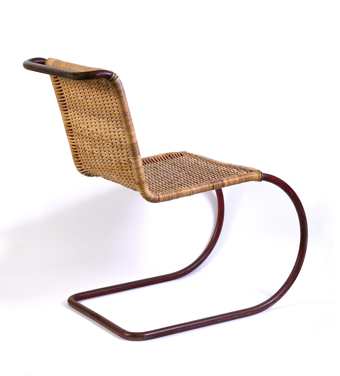 An armless chair with a wicker with the back and seat in one continues weave. The chair is supported by a tube base rather than conventional legs. 