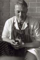 Black and white photograph of the upper profile of Lewis Boam holding a kitten.