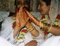 Colour photograph of Rashida and Inayat Hassanali with Mehndi decorated hands, 1995.