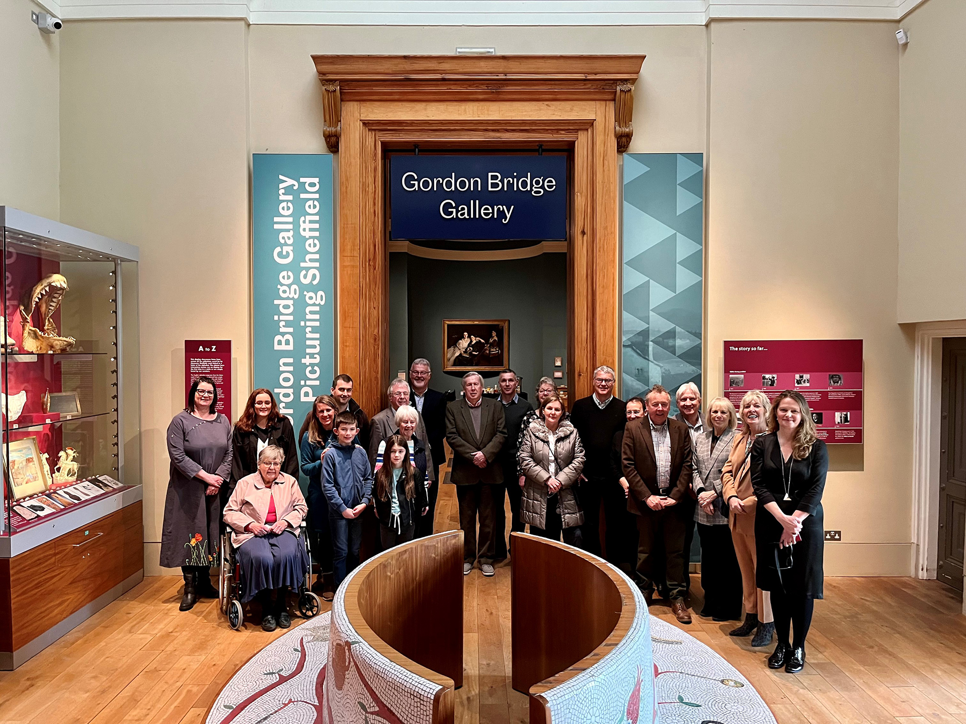 A group of people gathered in front of the entrance to the Gordon Bridge Gallery at Weston Park Museum.  