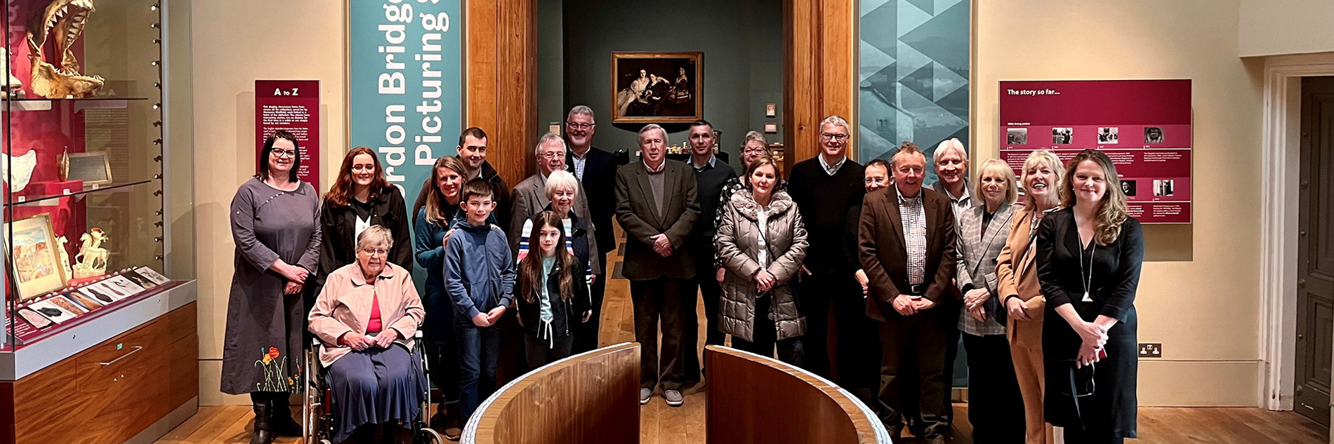 A group of people gathered in front of the entrance to the Gordon Bridge Gallery at Weston Park Museum.  