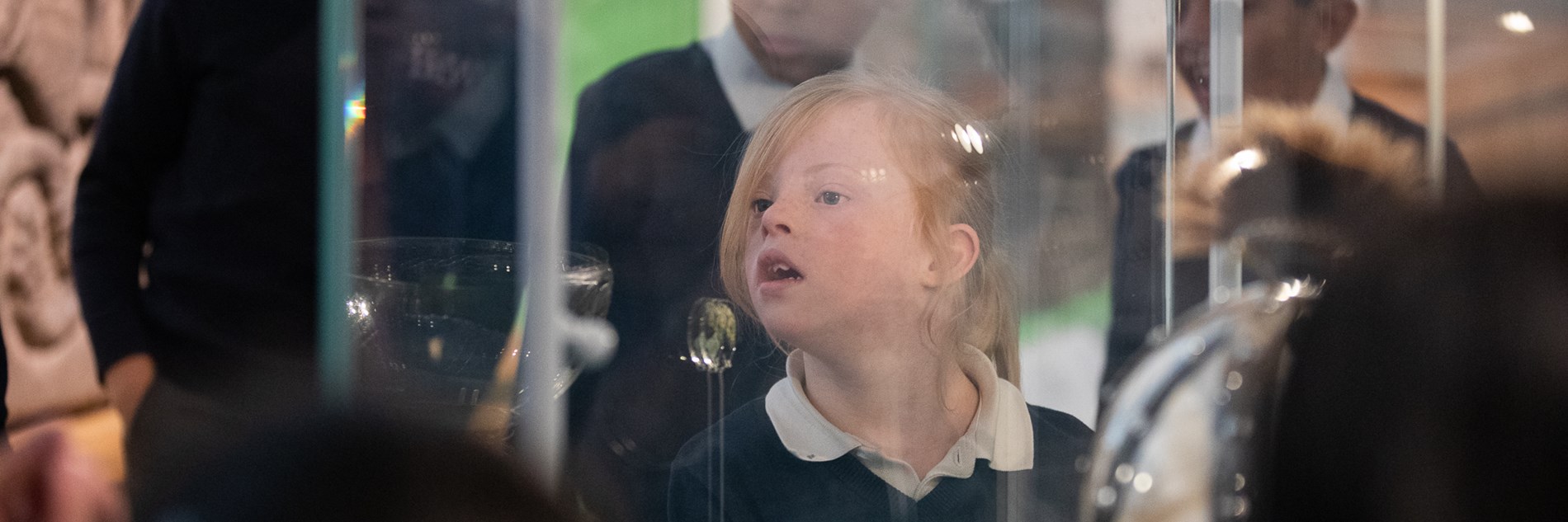 A primary school aged child, seen through a glass exhibition case.