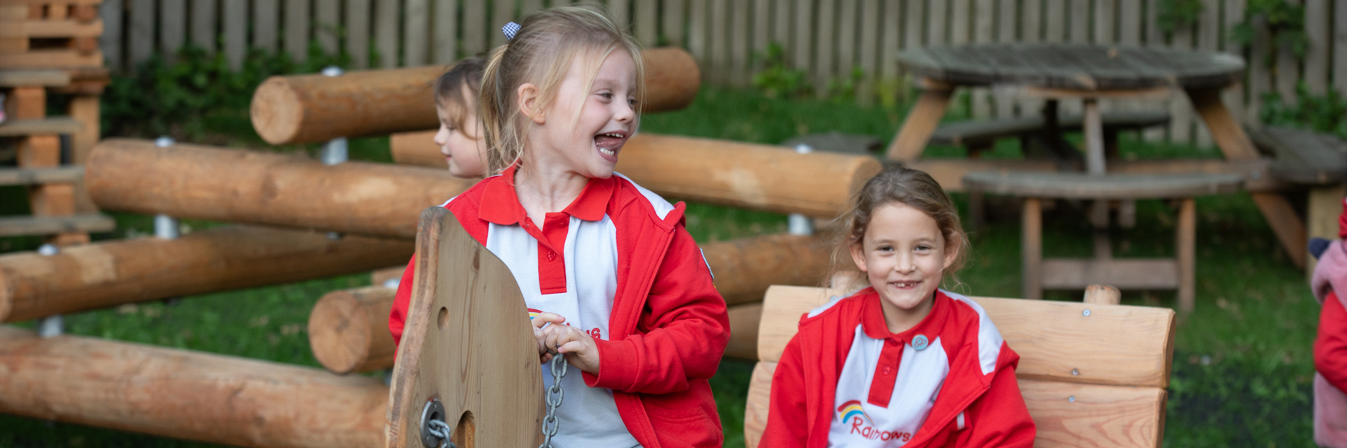 Two children play on a wooden horse and cart in a outdoor play area