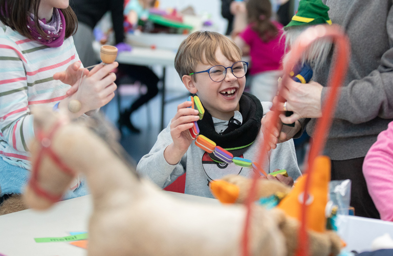 A child laughing while taking part in a schools workshop. 