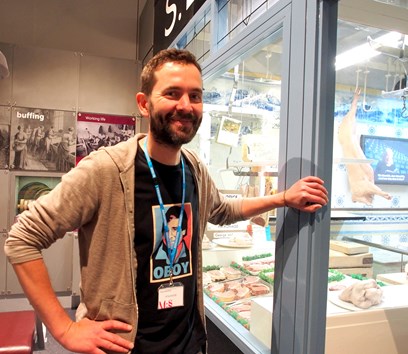 An adult stood in front of a replica butchers shop in a museum gallery 