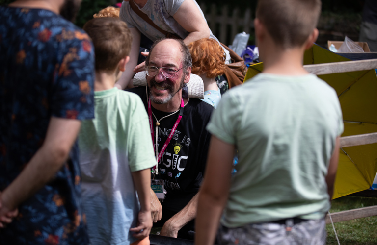 An adult talking to two children in a busy outdoor space 