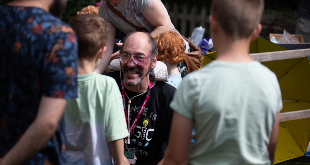 An adult talking to two children in a busy outdoor space 