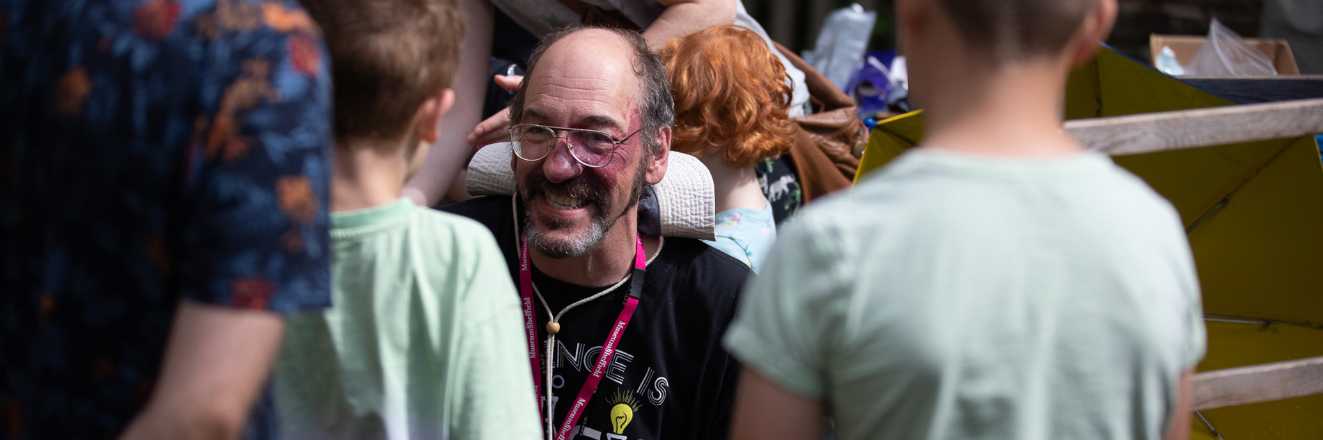 An adult talking to two children in a busy outdoor space 