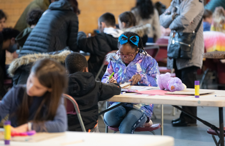 A group of people, mainly children, doing various craft activities. 