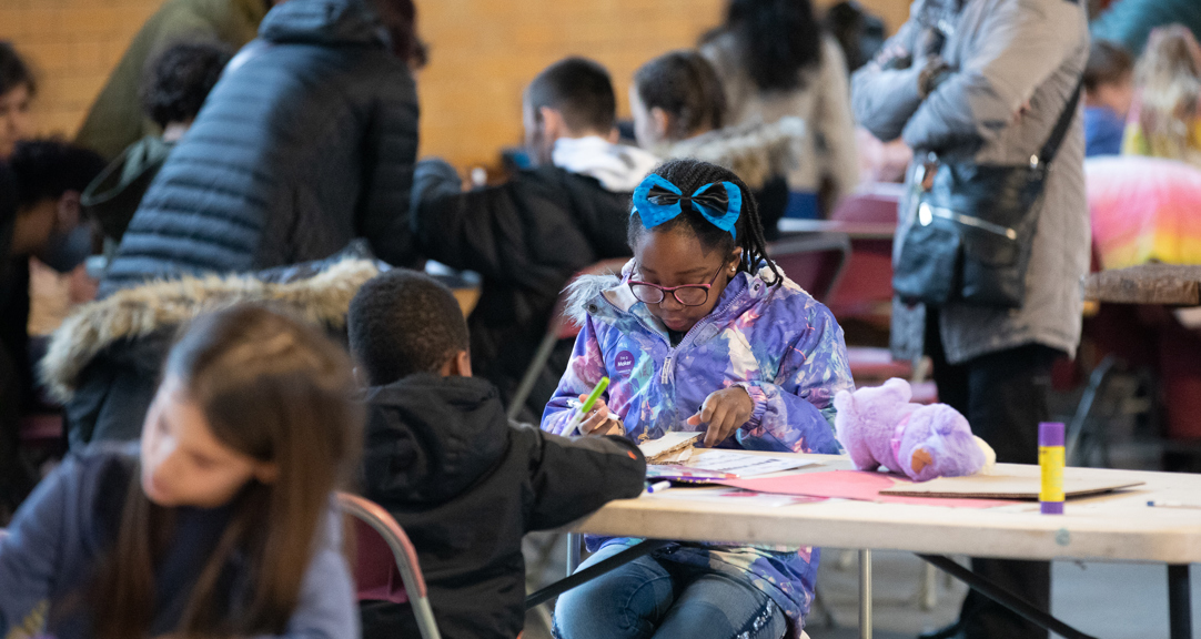 A group of people, mainly children, doing various craft activities. 