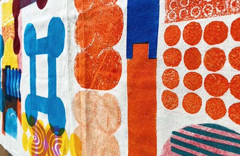 A photograph of material with orange, yellow and blue geometric shapes printed on it