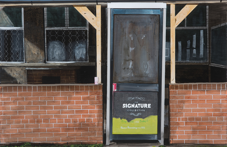 A waist high brick wall in front flats or houses - just off centre in the wall is a full size door with a panel on the bottom which says  The Signature Collection