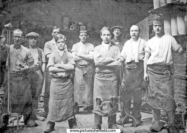 A black and white photograph of nine male steel workers, all looking defiantly into the camera.