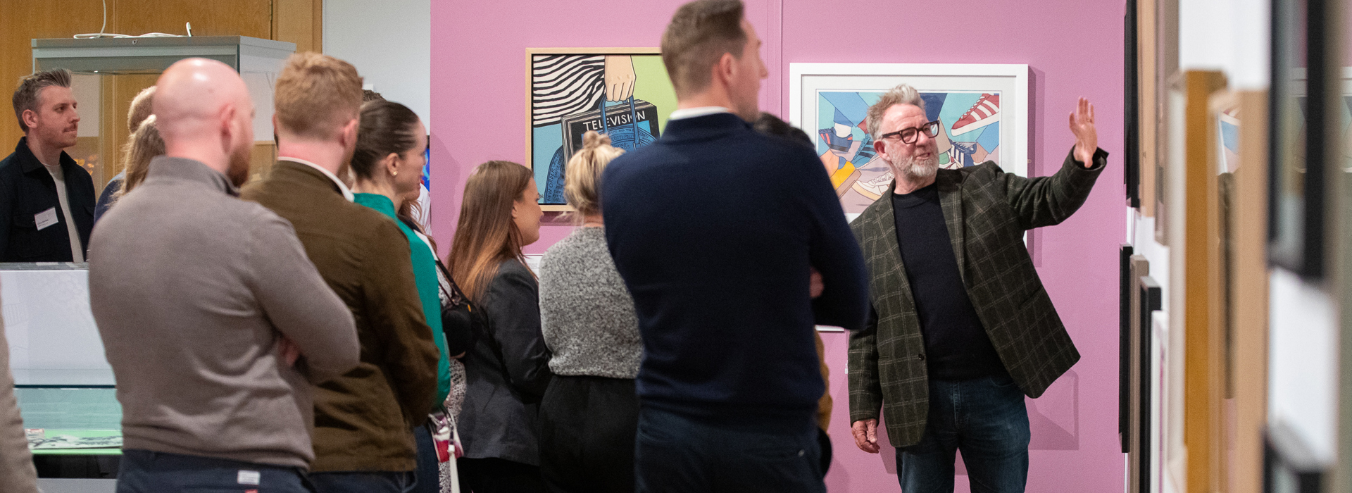 A group of people listen as an artist talks about his work in an art gallery 