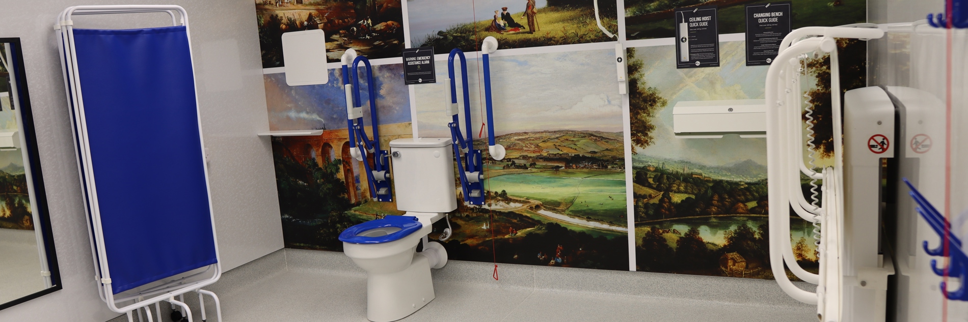 The changing places toilet, showing half the room with some facilities pictured, including the toilet, grab rails, bed and hoist.