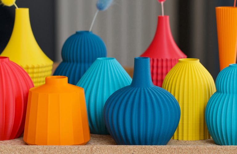 A collection of coloured vases in red, orange, yellow, blue and turquoise. The vases vary in size and shape, but each has a ridged or textured surface.