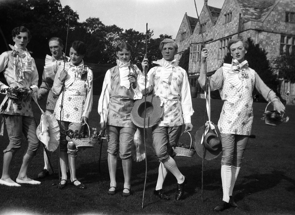 A black and white photograph of a group of adults in the gardens of a large house.  