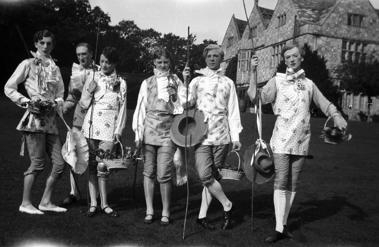 A black and white photograph of a group of adults in the gardens of a large house.  