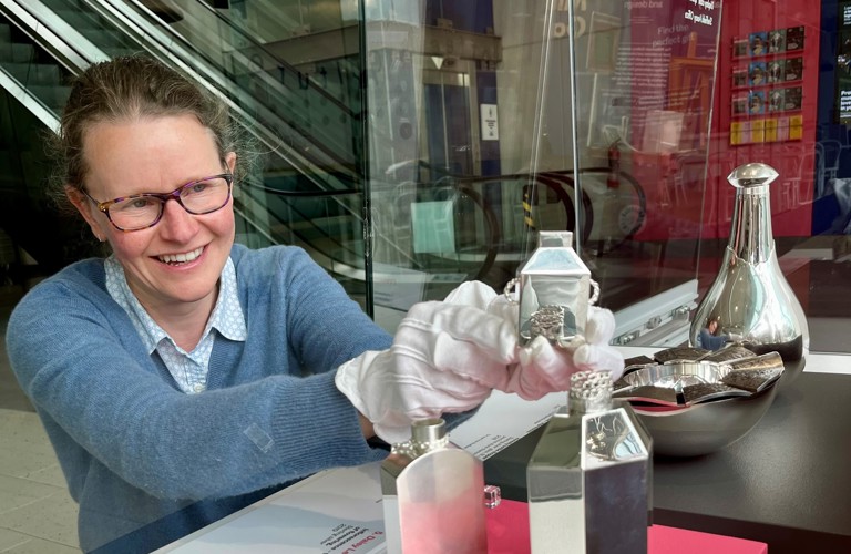 An adult installing silverware into a display case in a museum gallery 
