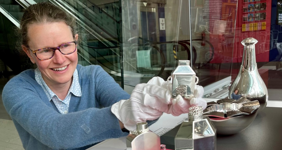 An adult installing silverware into a display case in a museum gallery 