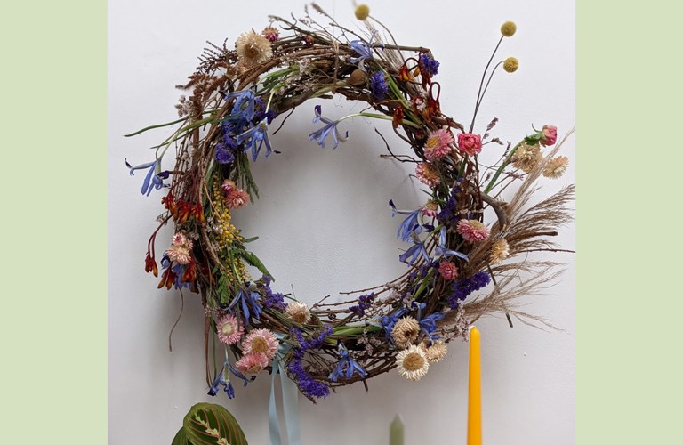 A photograph of a springtime wreath with lots of delicate flowers. Photographed against a white background