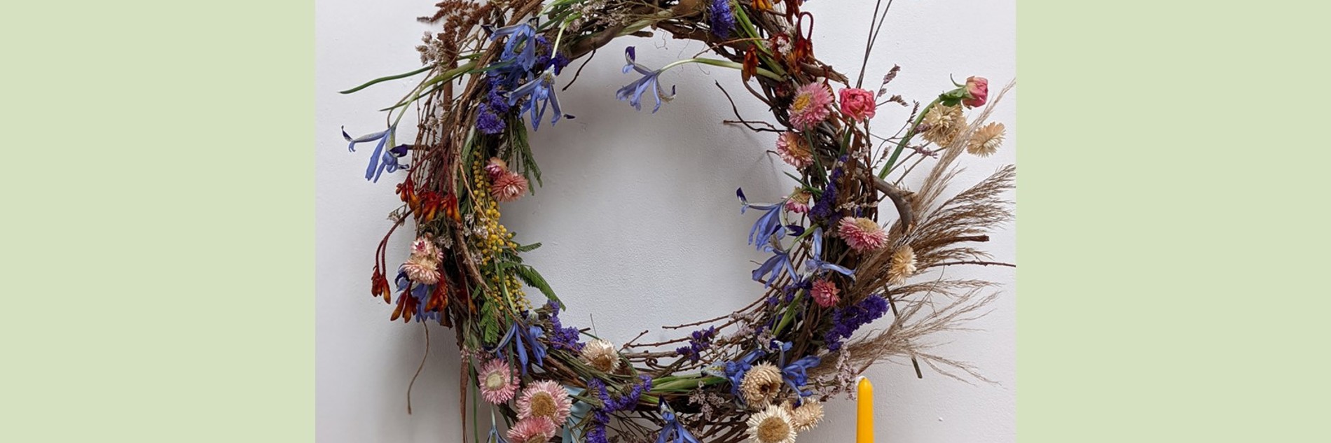A photograph of a springtime wreath with lots of delicate flowers. Photographed against a white background