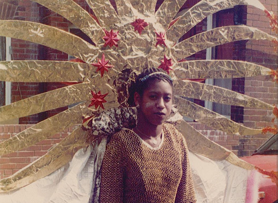 A photograph of a woman in a carnival costume including an ornate gold headdress and cape.