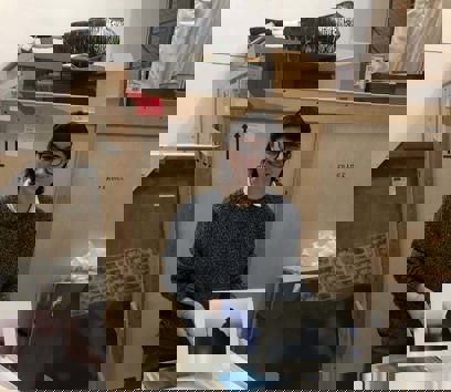 Volunteer in a Museum storage room looking at a portfolio of black and white photographs and holding one to the camera.  
