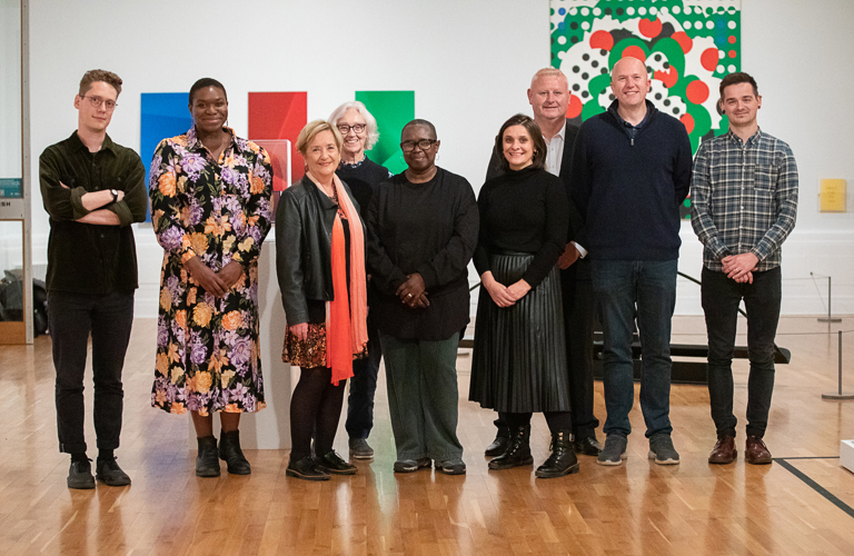 A group of adults in front of two artworks in a gallery 