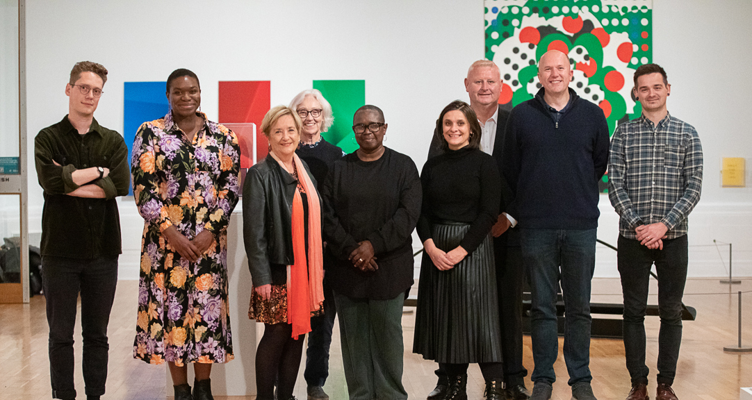 A group of adults in front of two artworks in a gallery 