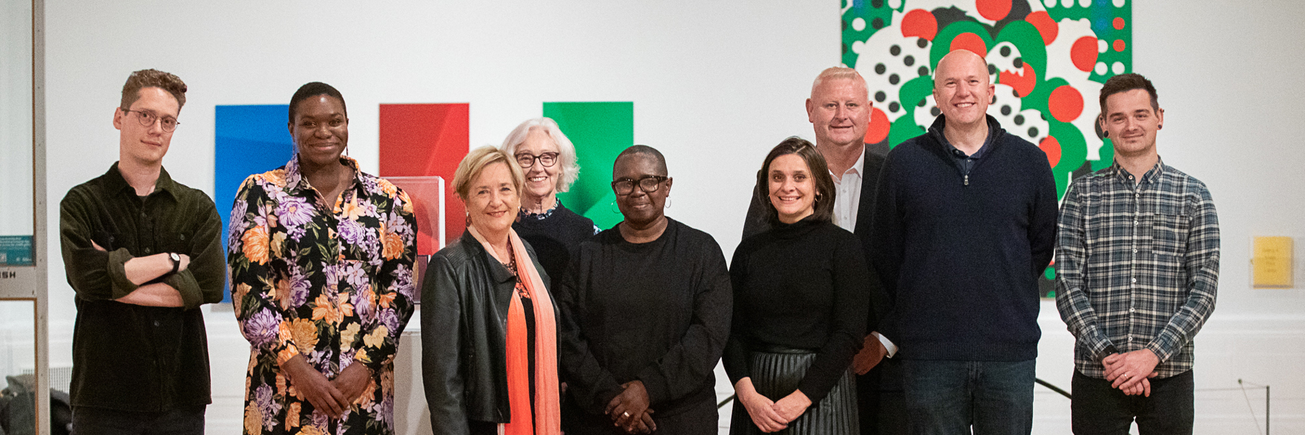 A group of adults in front of two artworks in a gallery 