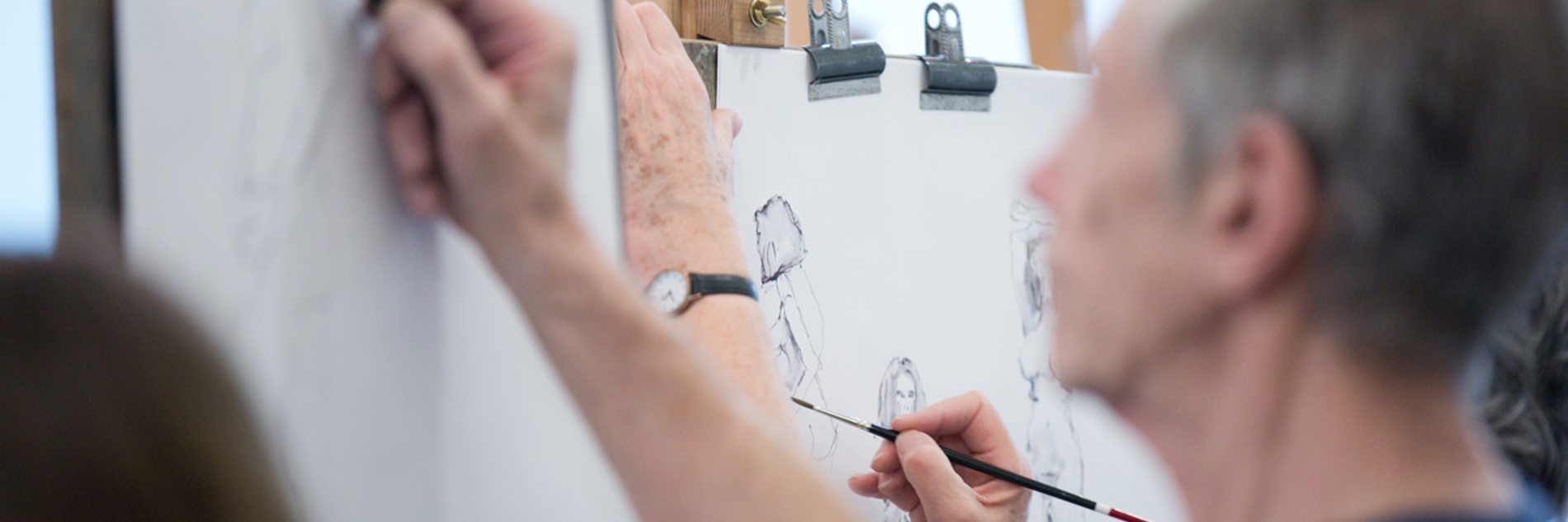 A photograph of an adult drawing on an easel. 