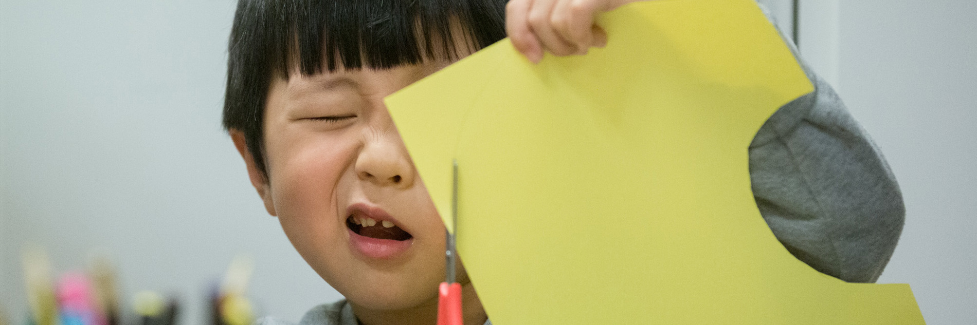 A very focused child cutting paper held close to their face. 