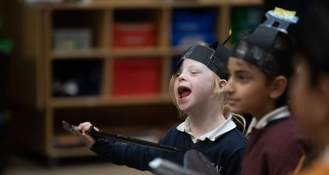 Two children wearing paper helmets and holding clipboards.  