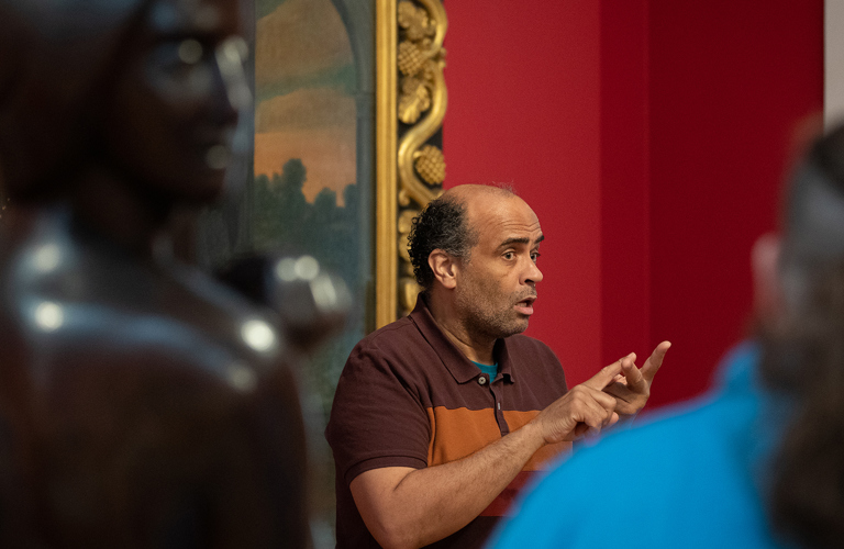 A tour guide using BSL communicates with a group in a gallery.