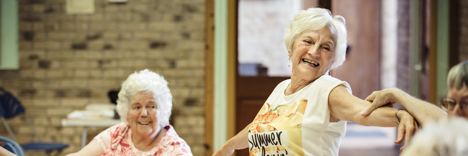A group of seated and standing older adults linking arms whilst dancing