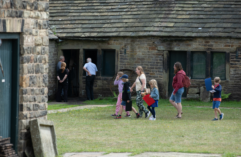A group of children and adults walking in front of a building. 