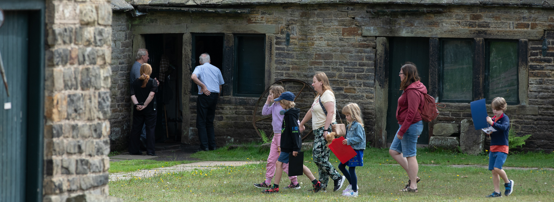 A group of children and adults walking in front of a building. 