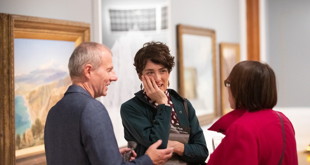 Three adults in conversation in an art gallery 
